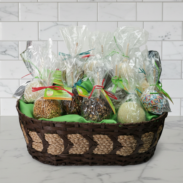 Wicker basket with wrapped caramel apple gifts on a marble surface and tiled wall background